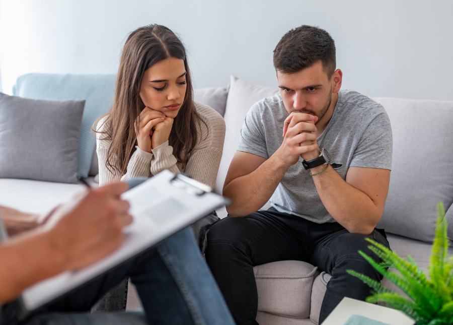 Two people sitting on a couch with their hands on their knees