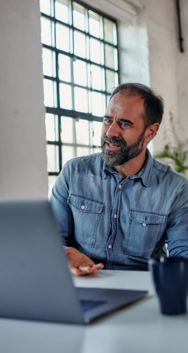 A person sitting at a table with a laptop and a cup of coffee