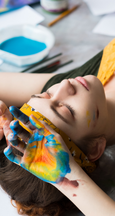 a person laying on the floor with their hands painted with colorful paint